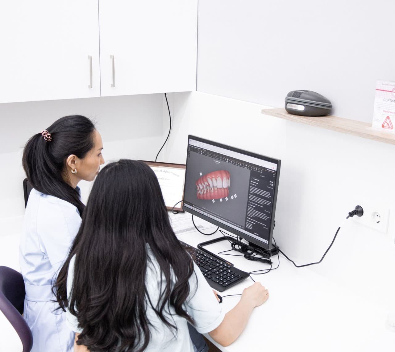 Clinician reviewing a dental CAD design on screen at the lab